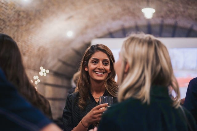 two ladies speaking to each other with drinks in hand at a networking event