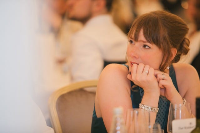 lady listening attentively to another person at the dinner table, hands on chin