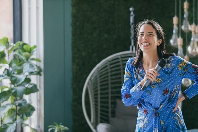 lady on stage with microphone  and phone with a big smile