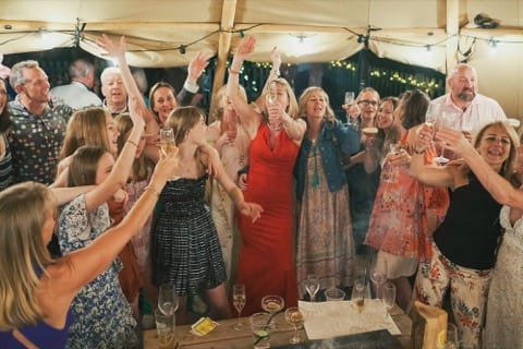 large party gathering a celebrations around a wooden table