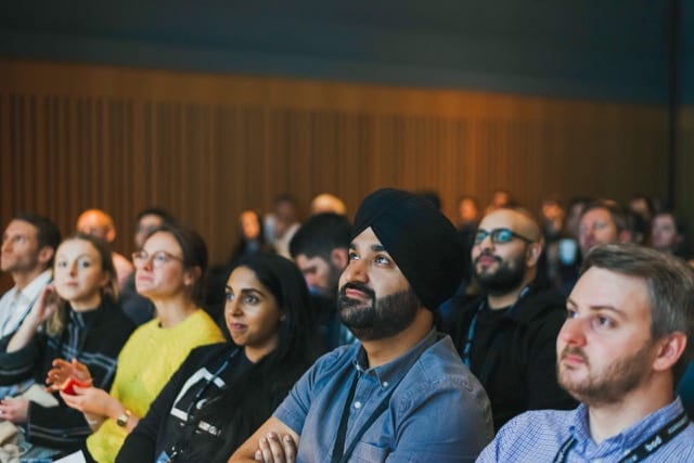 people sitting in a row of chairs listening attentively to a talk