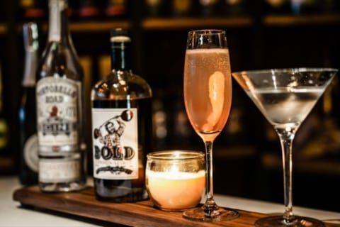 a bottle of bold cinnamon spirit, a candle and a cocktail