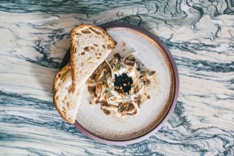 a top down photo of a mushroom salad with a side of sourdough bread
