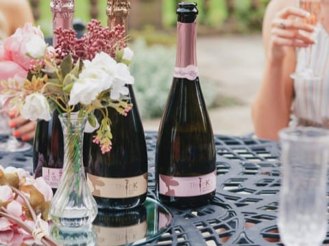 two bottles of think prosecco on an outside garden table