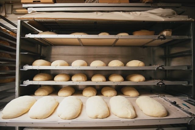 racks of kneaded dough in a bakery stacked up, another rack is about to be placed in the rack