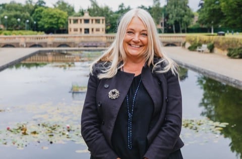 blonde lady smiling in front of a pond