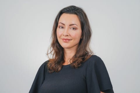 brunette lady smiling toward camera with white backdrop
