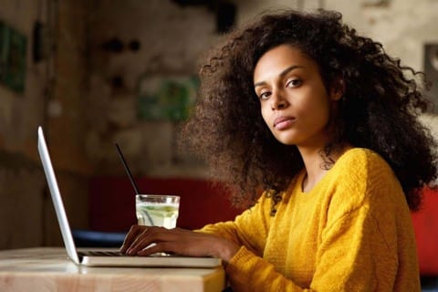 mixed-race lady looks to her left with lapdop in hand