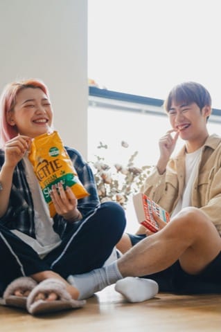 two friends eat snacks and laugh