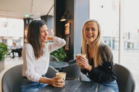 two girls smiling while having a coffee
