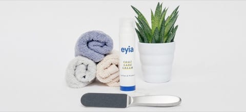 eyia foot care cream product with towls, and aloe vera beside it