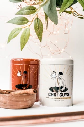 two tins of chai tea with a bowl of cinnamon bark beside it