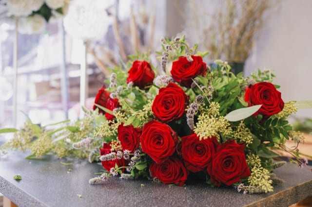 a bouquet of red roses place on its side on a table