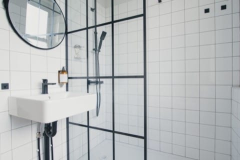 a clean white bathroom with strong black metal finishes