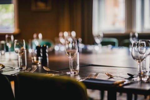 a elegantly dressed dining table with glasswear and cutlery, waiting for guests to arrive