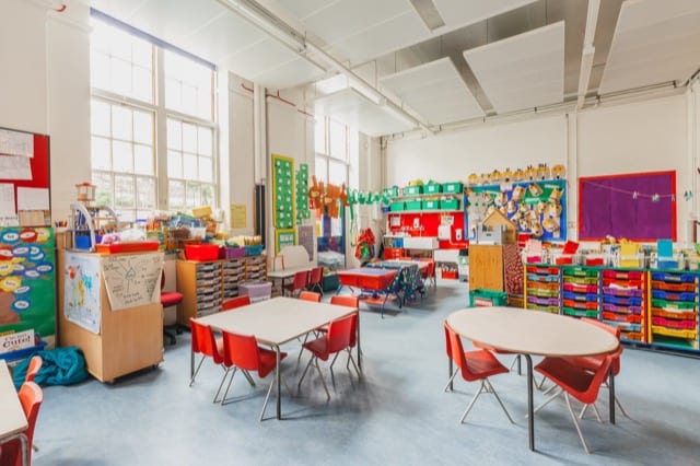 a tidy and colorful classroom with tables and shelves full of paper, covers and art materials