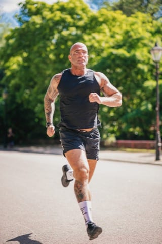 a bald white man in a black vest runs