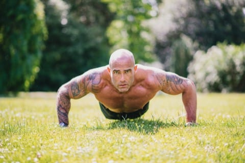 the same bald man looks at the camera while doing a press up