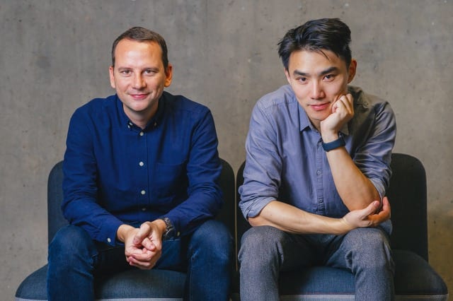 Dennis with hands grasped and Tony arms perpendicularly cross from Perfocal are sitting down smiling.