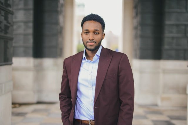 Black man in a burgundy suit and blue shirt poses in London for his professional headshots taken by perfocal