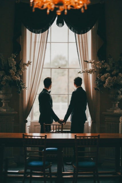 Couple hold hands at a town hall looking out through big windows, wedding photography silhouettes done by perfocal