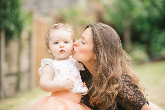mother kissing her baby daughter who's in a pink tutu