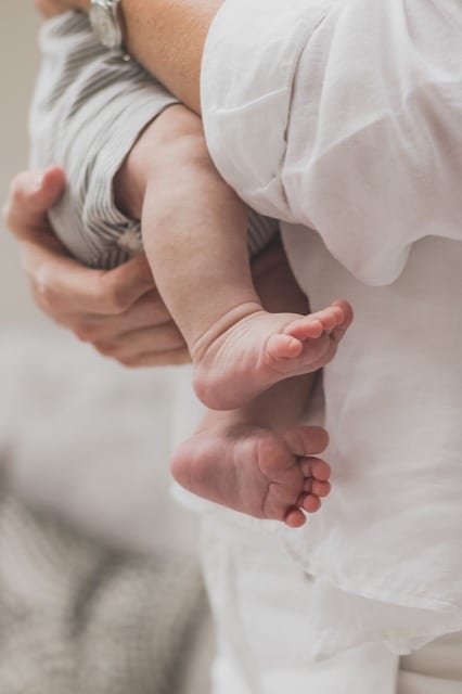 father's arms cradling their newborn baby