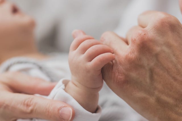 newborn baby holding parent's finger