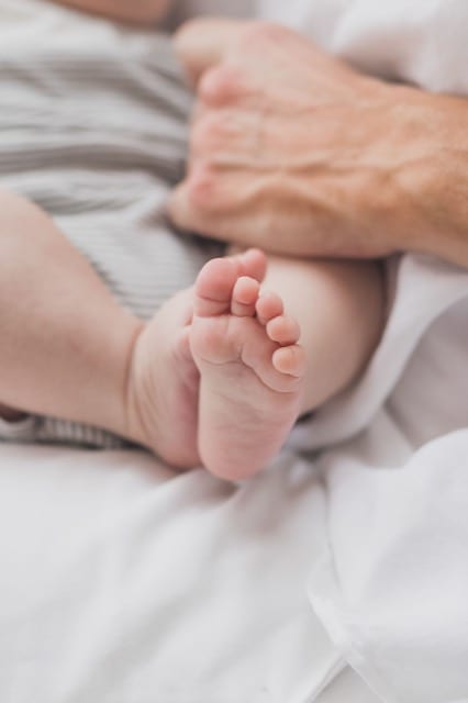 portrait of baby's tiny feet, being held by mother