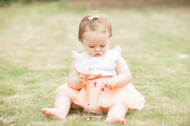baby in pink tutu playing with a flower