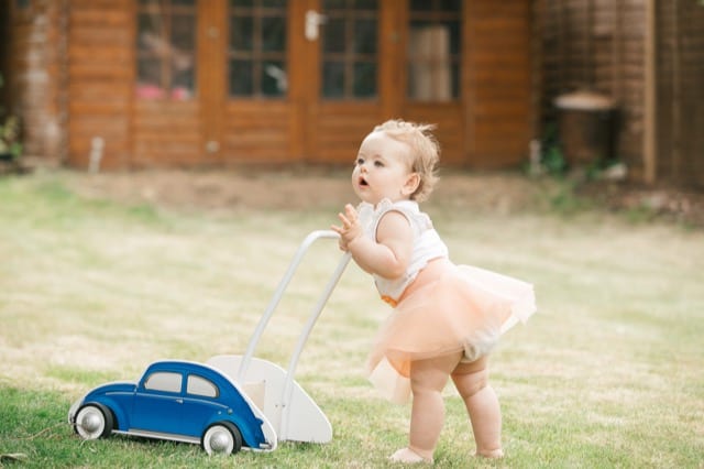 female baby with pink tutu playing on grass ground