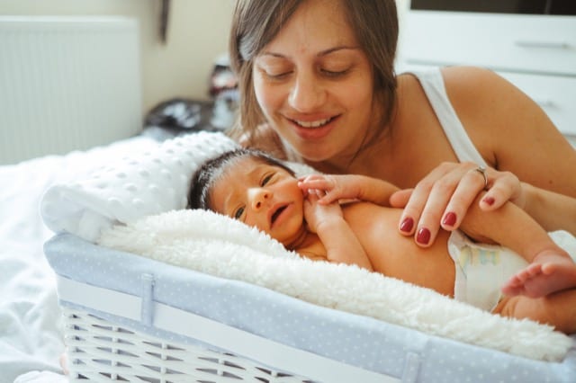 newborn baby in a basket with mother watching over