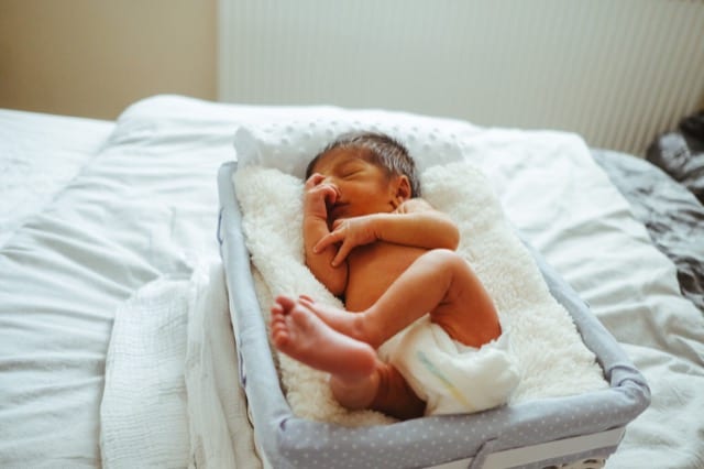 newborn baby in a nappy sleeping soundly in a wash basket getting photographed