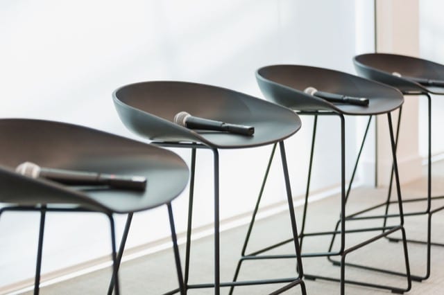 a line of four speaking stalls, each with a microphone rested on the seat