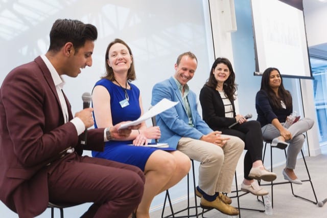 a panelist asks a questions to the other 4 panelists at a business event