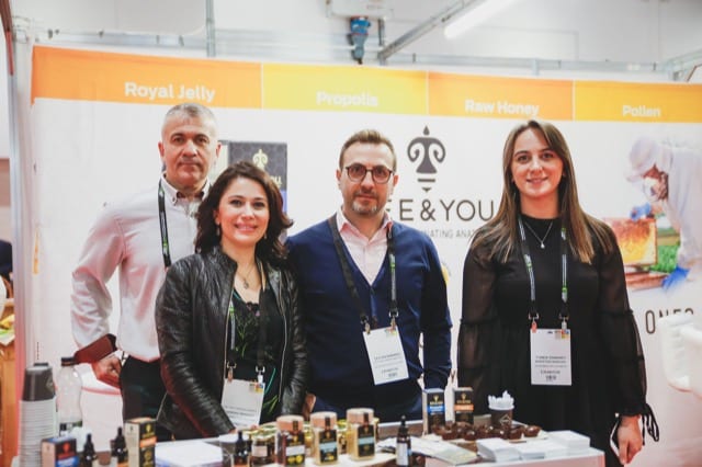 team of 4 pose for a perfocal photographer at a business convention in front of their stall