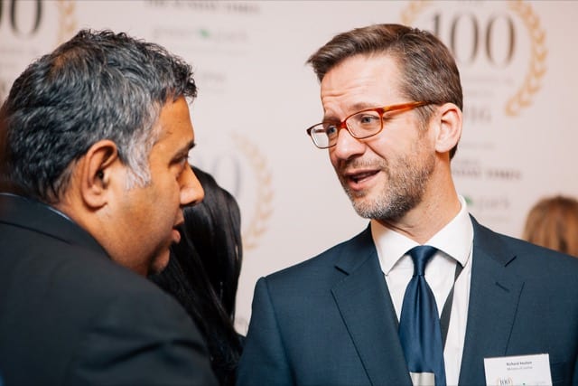 two gentlement speaking whilst having their photo taken at a centinary business event