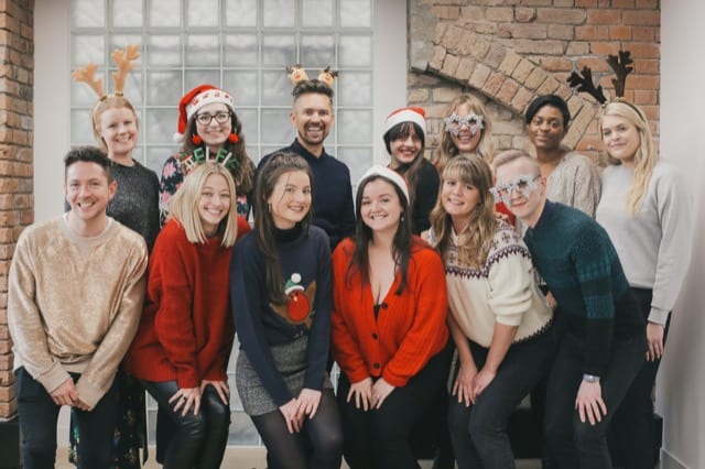 Employees pose in their xmas jumpers for their company christmas party photoshoot