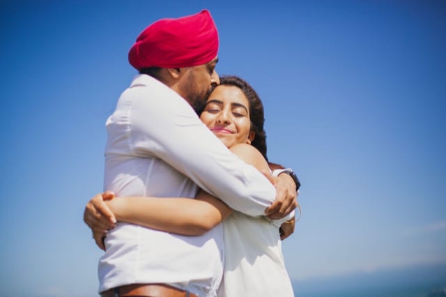 Couple embrace in the sun in front of blue sky