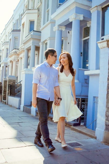 Asian couple walk down a street in london hand in hand for their couple photoshoot