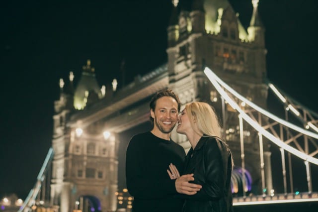 Couple pose for photoshoot at nighttime in front of Tower Bridge in London
