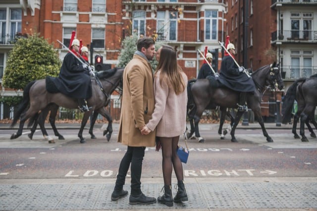 A couple kissing in front of a horse guard parade