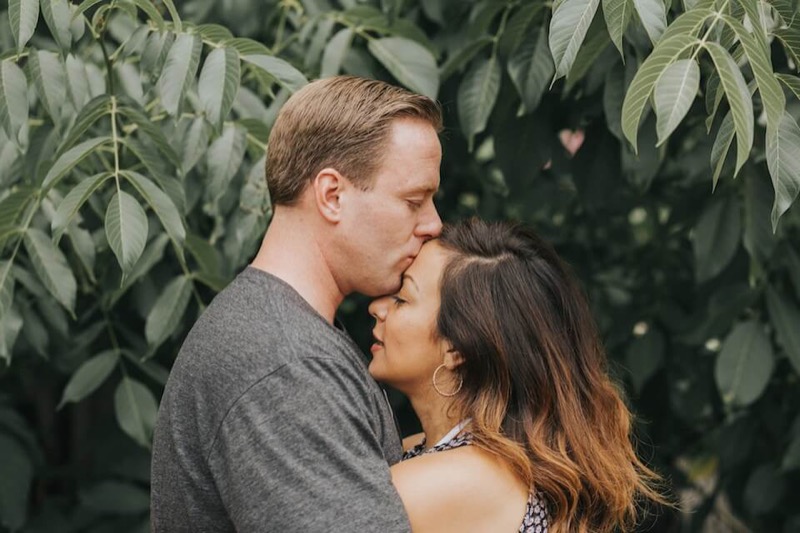 Man holds the face of his girlfiend whilst they stare into each other's eyes in a park in london