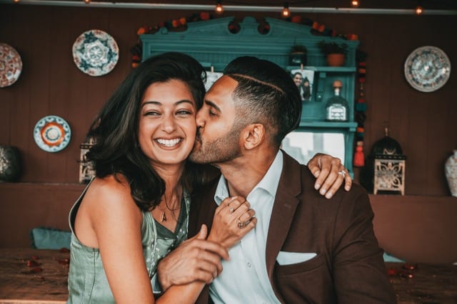 Asian man kisses fiancé on the cheek after proposing in London for a surprise engagement shoot
