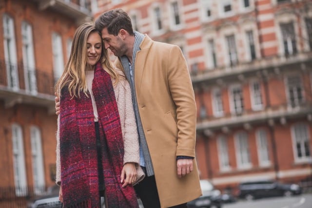 Man rests his head on his fiancé's at their perfocal enagagement photoshoot in kensington