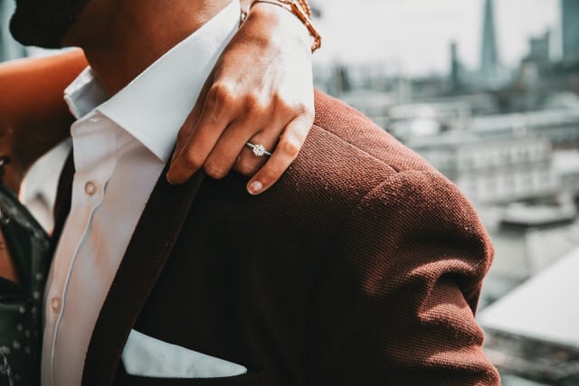 close up of a woman's engagement ring with her arm wrapped around her fiancé for an engagement shoot
