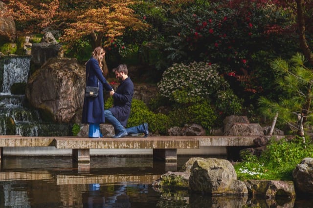 Man on one knee in Kyoto gardens, london proposing to his girlfriend on the bridge