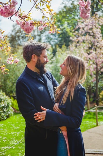 Couple in navy coats hug in Kyoto gardens, London, at their engagement photoshoot by perfocal