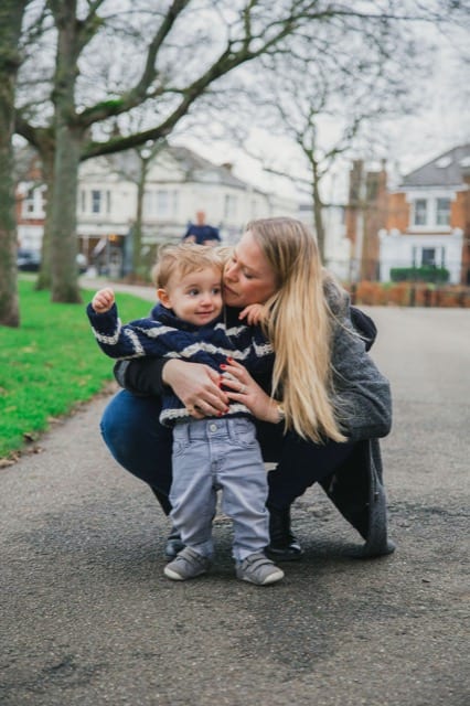 mum kisses son's cheek on a walking photoshoot in park