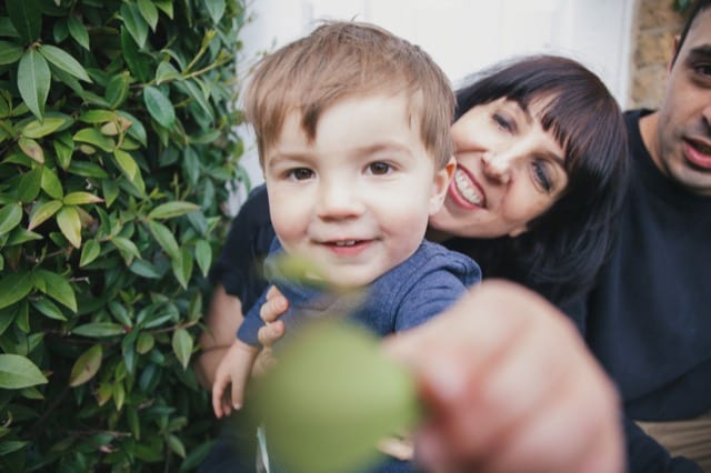 woman's toddler reaching towards the camera to grab a leaf from the photographer